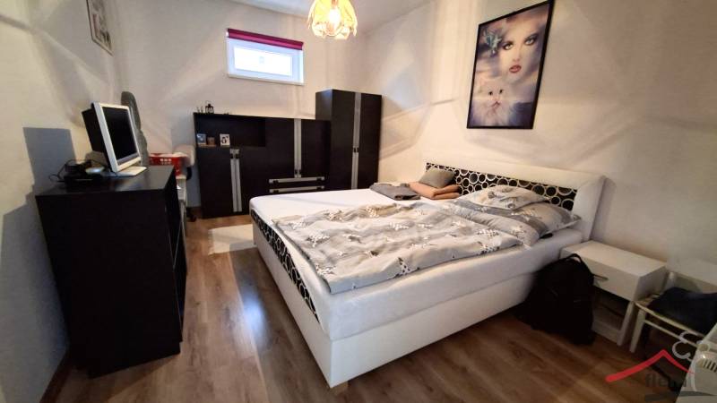 Schlafzimmer in einem Einfamilienhaus mit Holzboden, Bett und schwarzen Möbeln.