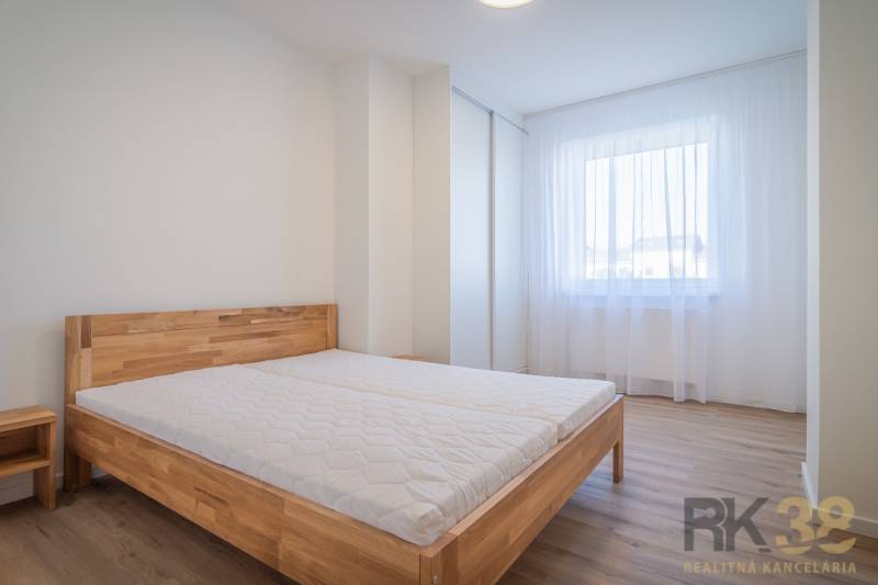 Helles Schlafzimmer mit Holzbett und Fenster in einer 2-Zimmer-Wohnung.