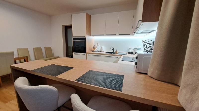 Küche in einer 2-Zimmer-Wohnung mit eingebauten Geräten und einem Boden in Holzoptik.