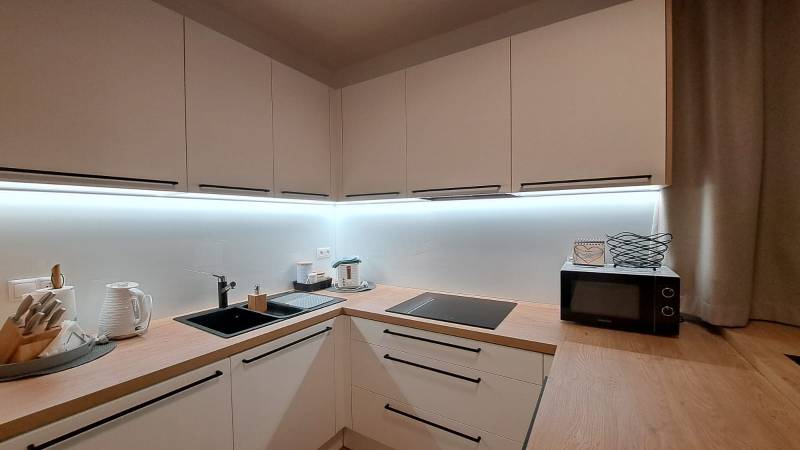 Küche in einer 2-Zimmer-Wohnung mit Holzelementen und Kochutensilien.