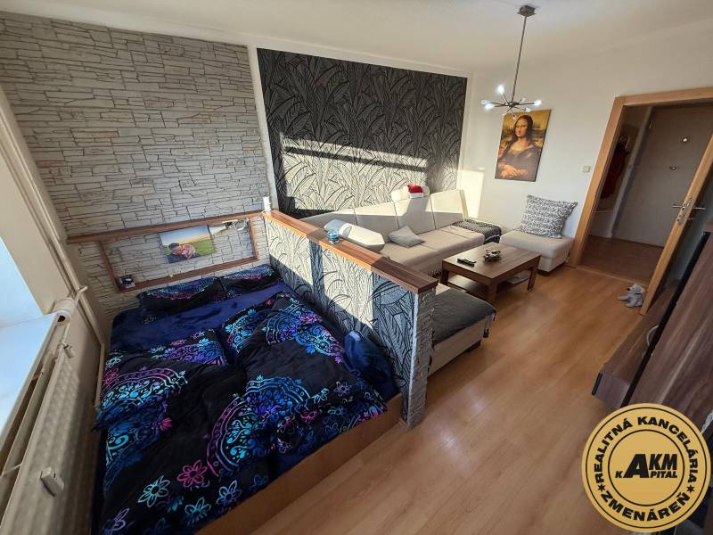 Wohnzimmer mit Sofa, Bett und Holzboden in einer 3-Zimmer-Wohnung.