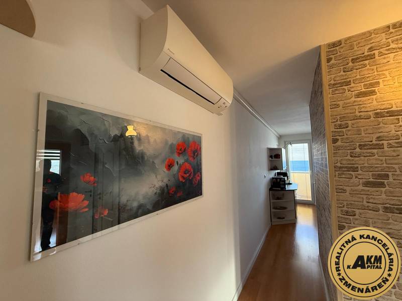 Flur in einer 3-Zimmer-Wohnung mit Holzboden, dekorativer Ziegelwand und Klimaanlage.