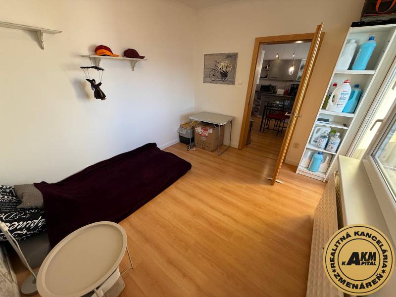 Ein Zimmer mit Bett und Ablageregalen, Boden mit Holzdekor in einer 3-Zimmer-Wohnung.