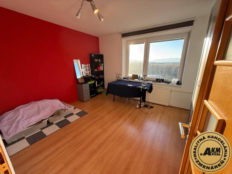 Ein Zimmer in einer 3-Zimmer-Wohnung mit einer roten Wand und einem Boden in Holzoptik.