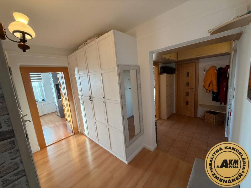 Der Flur in der 3-Zimmer-Wohnung mit einem Boden in Holzoptik, weißen Schränken und einem Spiegel.