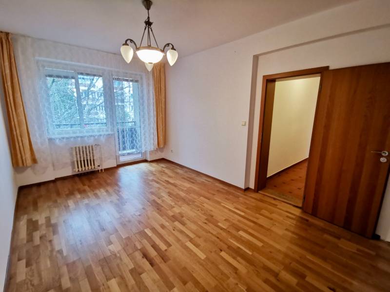 Zimmer einer Vierzimmerwohnung mit Holzboden und Vorhängen.