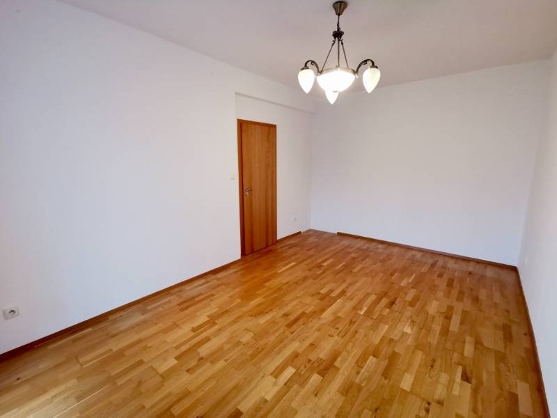 Ein Zimmer mit einem Holzboden und einer Leuchte in einer 4-Zimmer-Wohnung.