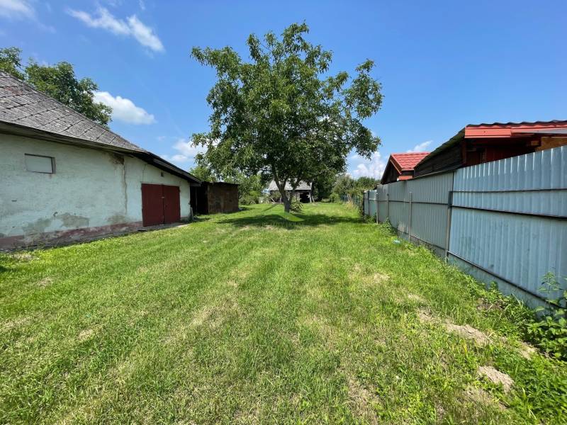Blick auf ein grünes Grundstück in Zemplínska Široká, ideal zum Wohnen, mit sichtbaren Gebäuden.