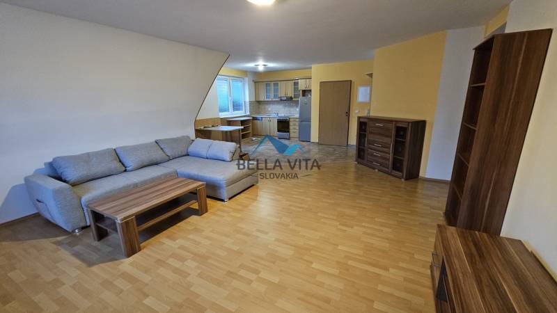 Ein Interieur mit einem Sofa, einer Küche und einem Holzboden in einem Gebäude.