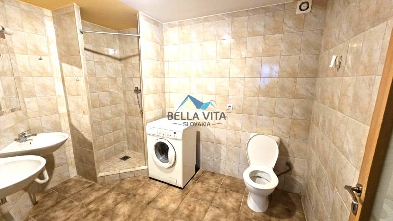 Badezimmer mit Waschmaschine, Dusche und Toilette. Wände mit Keramikfliesen und Boden mit Dekor.