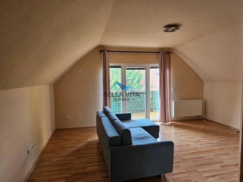 Innenraum eines Gebäudes mit Holzboden, Sofa und Balkon.