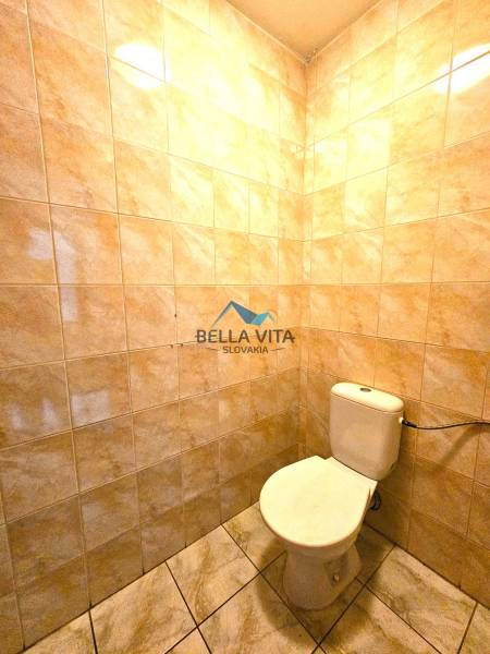 Eine Toilette im Gebäude mit Keramikfliesen und einem Boden mit Marmoroptik.