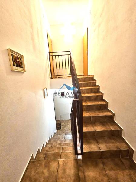 Treppenhaus im Gebäude mit Fliesenverkleidung und Geländer, beleuchtet von weißem Licht.