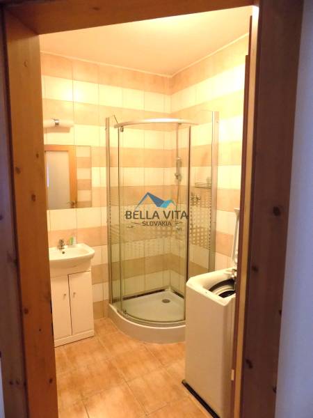 Badezimmer in einem Gebäude mit Fliesen, Duschkabine und Waschmaschine.