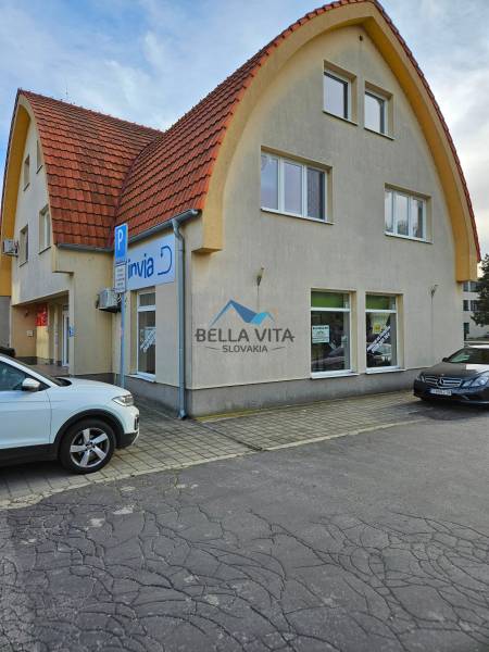 Das Gebäude am Kinderspielplatz in Galanta mit einem gewölbten Dach und Parkplätzen.