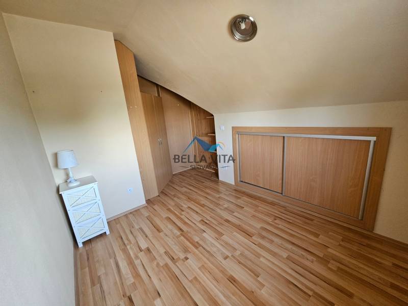 Ein Zimmer mit einem Holzboden, einem Einbauschrank und einem Nachttisch.