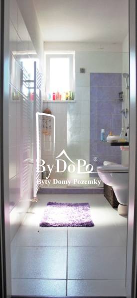 Badezimmer in einer Einzimmerwohnung mit Toilette, Waschbecken und Fenster. Helle Fliesen sind dominant.