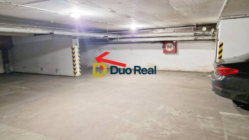 Unterirdischer Parkplatz in der Garage mit einem Stellplatz an der Wand und Autos.