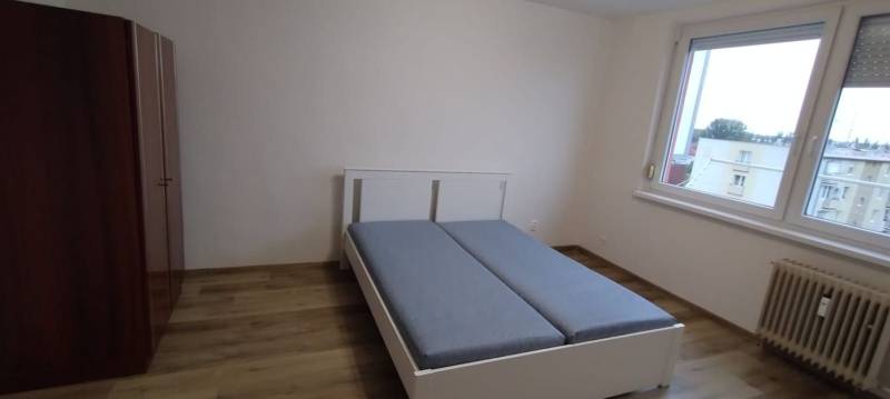 Schlafzimmer in einer Einzimmerwohnung mit Bett, Schrank und Boden in Holzoptik.