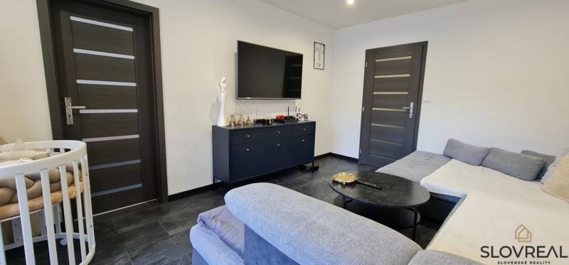 Wohnzimmer in einer Zweizimmerwohnung mit dunklem Boden und Sofa.