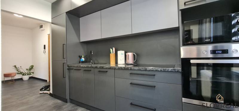 Eine stilvolle Küche mit modernen Geräten und dunklem Möbeldesign in einer 2-Zimmer-Wohnung.