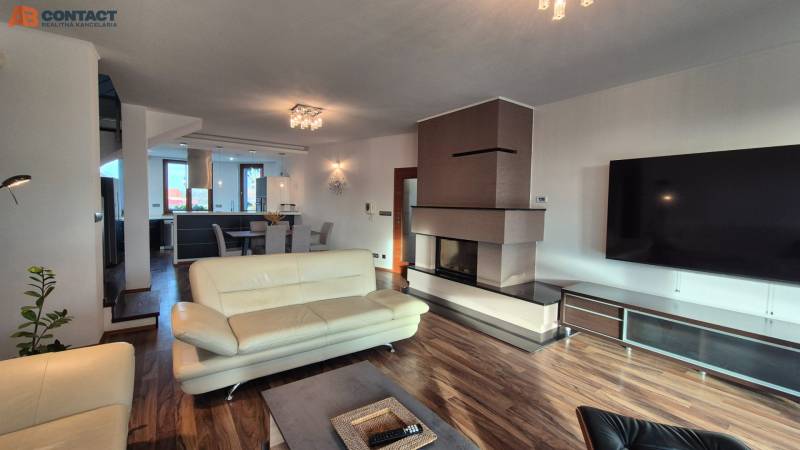 Ein geräumiges Wohnzimmer mit Kamin in einem Einfamilienhaus, helle Möbel, Boden mit Holzdekor.