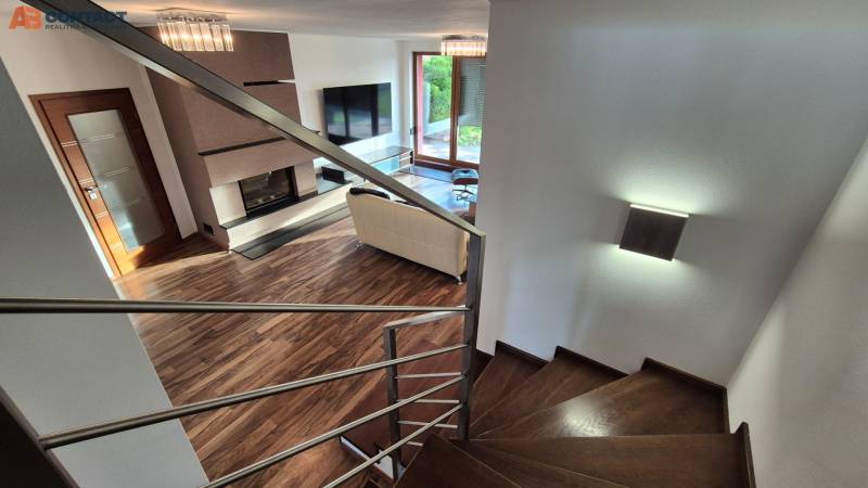 Wohnzimmer mit Kamin und Treppe in einem Einfamilienhaus, Bodenbelag mit Holzdekor.