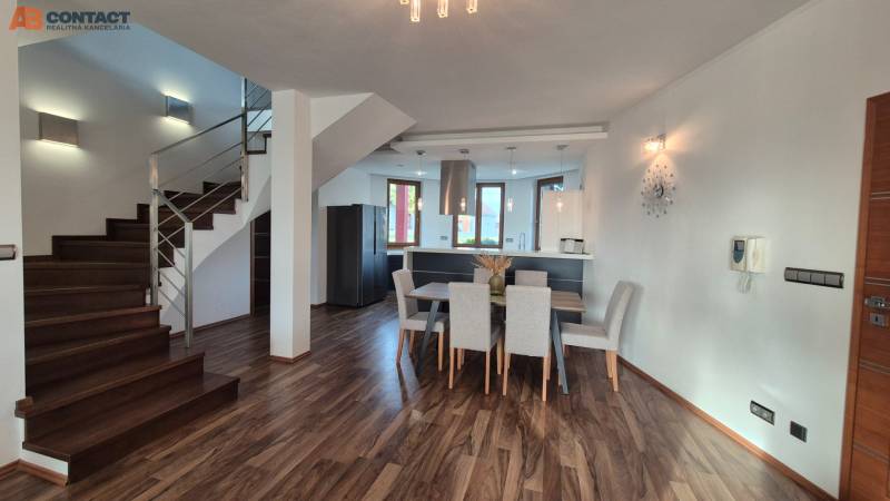 Innenraum eines Einfamilienhauses mit Küche, Esszimmer und Treppe auf einem Boden mit Holzdekor.