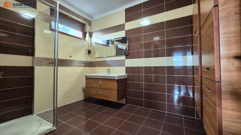 Badezimmer mit braun-cremefarbenen Fliesen, Dusche und Waschbecken, Einfamilienhaus.