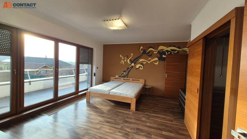 Ein Zimmer in einem Einfamilienhaus mit einem Boden in Holzoptik, einem Doppelbett und einer Terrasse.