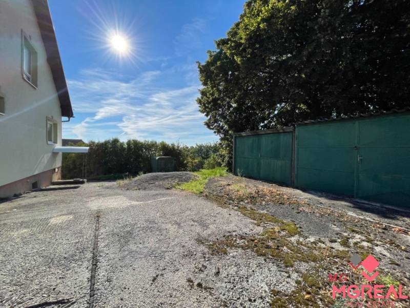 Einfamilienhaus in Podhradí in der Hauptstraße mit Garage, Baum und Betonoberfläche.
