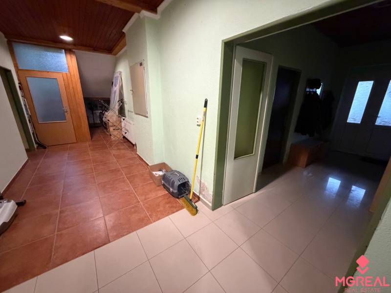 Der Flur eines Einfamilienhauses mit Fliesen, Türen und Kleiderhaken.