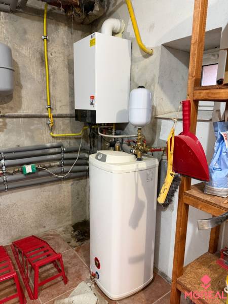 Heizung und Wasserspeicher im Keller eines Einfamilienhauses mit Ausstattung auf dem Regal.