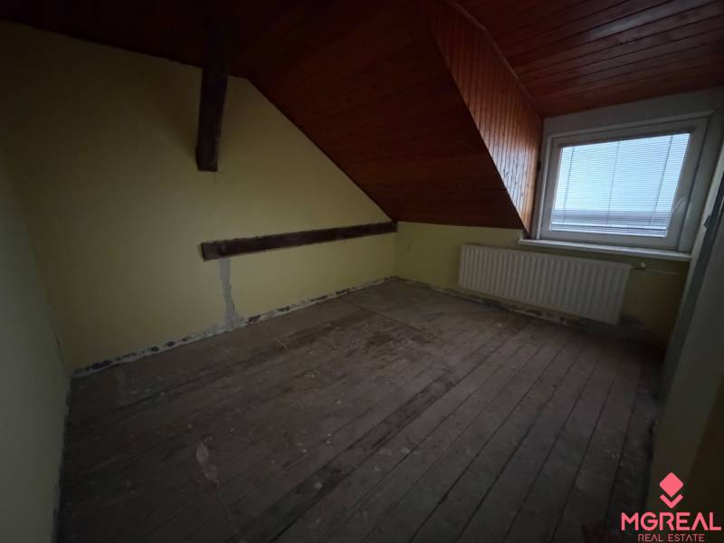 Dachgeschosszimmer in einem Einfamilienhaus mit Balken und Dachfenster.