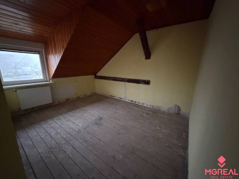Ein Dachzimmer mit einer Holzdecke und einem Boden mit Holzdekor in einem Einfamilienhaus.
