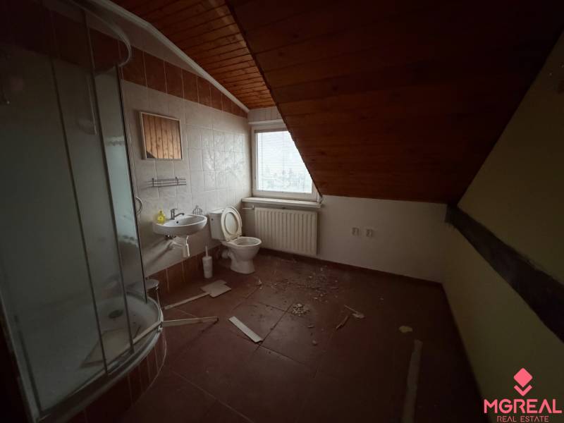 Badezimmer in einem Einfamilienhaus mit Waschbecken, Duschkabine und Holzverkleidung an der Decke.