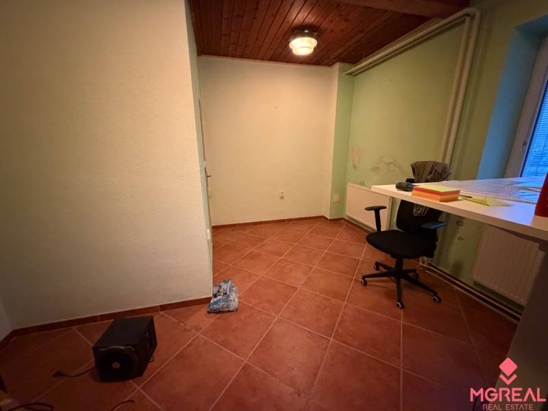 Izba v rodinnom dome s kachličkovou podlahou, stolom, stoličkou a stropným svietidlom.