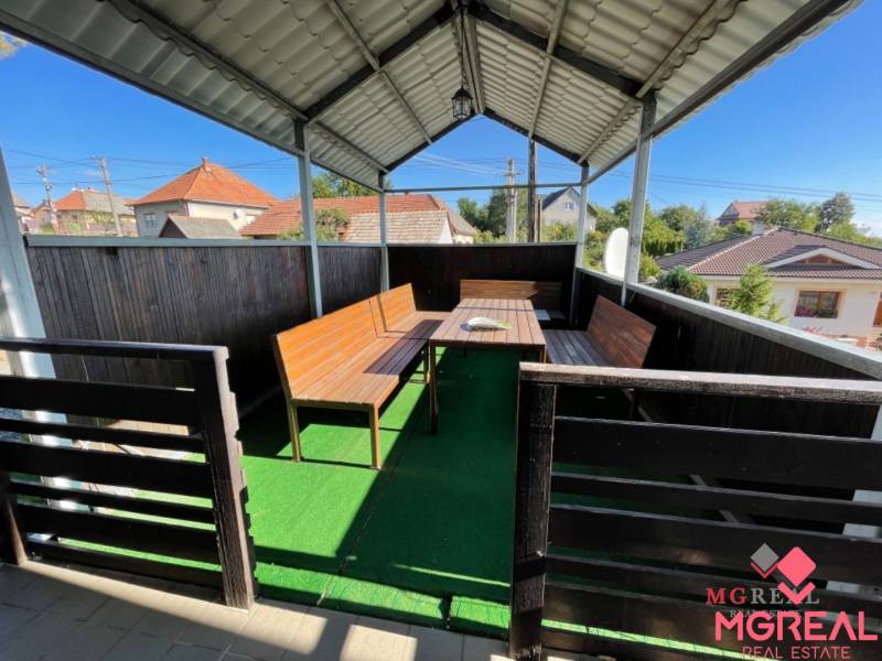 Überdachte Terrasse eines Einfamilienhauses in der Hauptstraße in Podhradie mit Holzmöbeln und Kunstrasen.