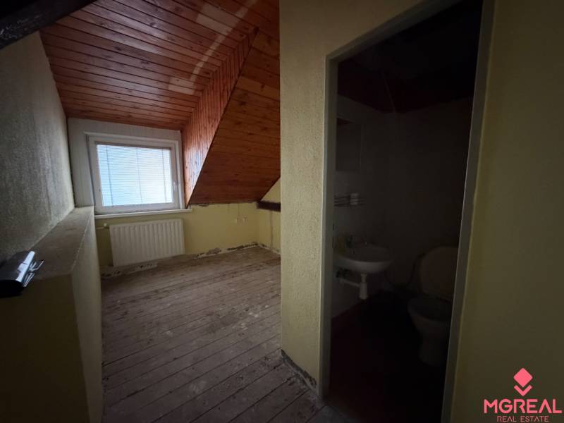 Dachgeschosszimmer mit Holzdecke und angrenzendem Badezimmer in einem Einfamilienhaus.