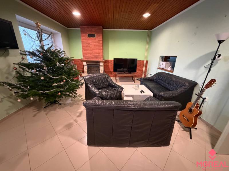 Wohnzimmer in einem Einfamilienhaus mit Weihnachtsbaum, Kamin und Gitarre in der Ecke.