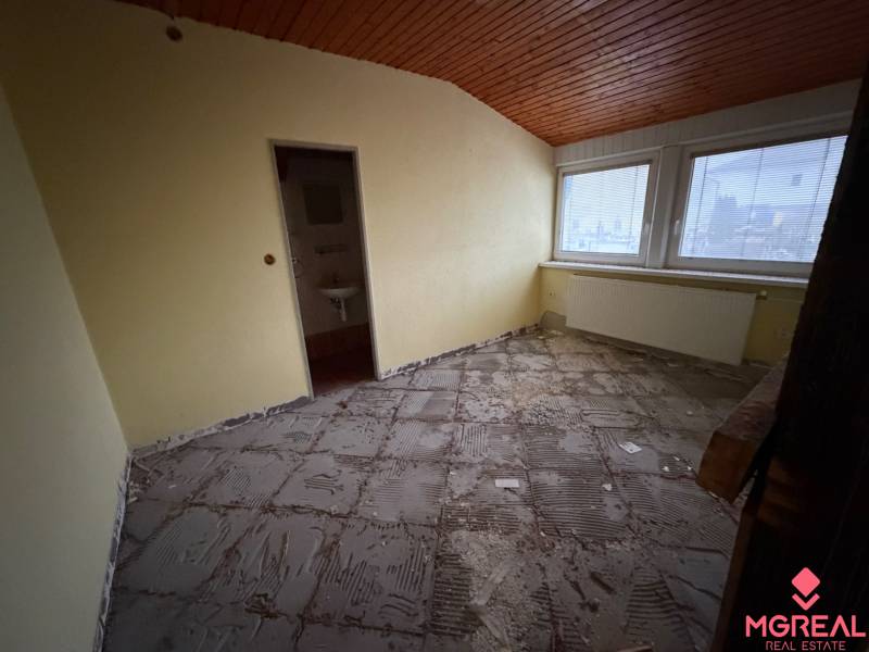 Ein Zimmer in einem Einfamilienhaus mit unfertigem Boden und einer Holzdecke.