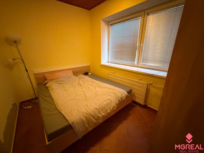 Schlafzimmer im Einfamilienhaus mit Ehebett, Lampe und großem Fenster mit Jalousien.