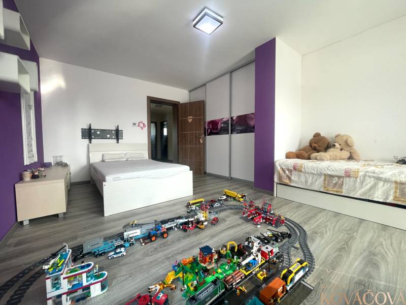 Kinderzimmer in einem Einfamilienhaus mit Bett, Spielzeug und Boden in Holzoptik.