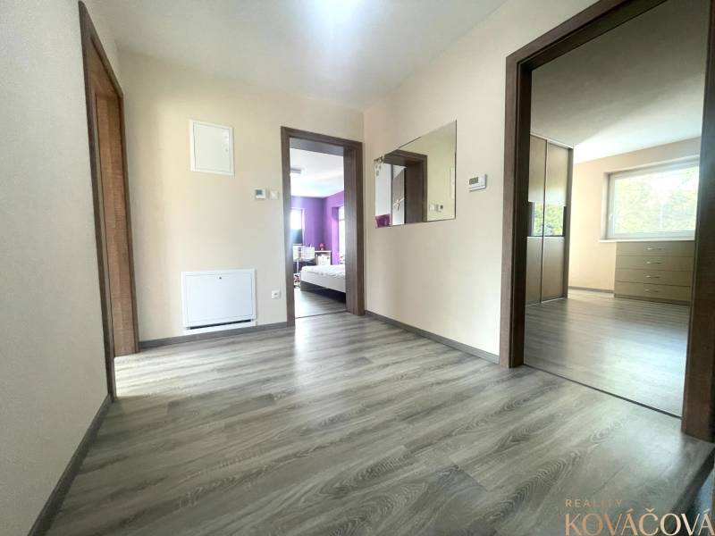 Ein Flur in einem Einfamilienhaus mit einem Boden in Holzoptik und einem Spiegel an der Wand.