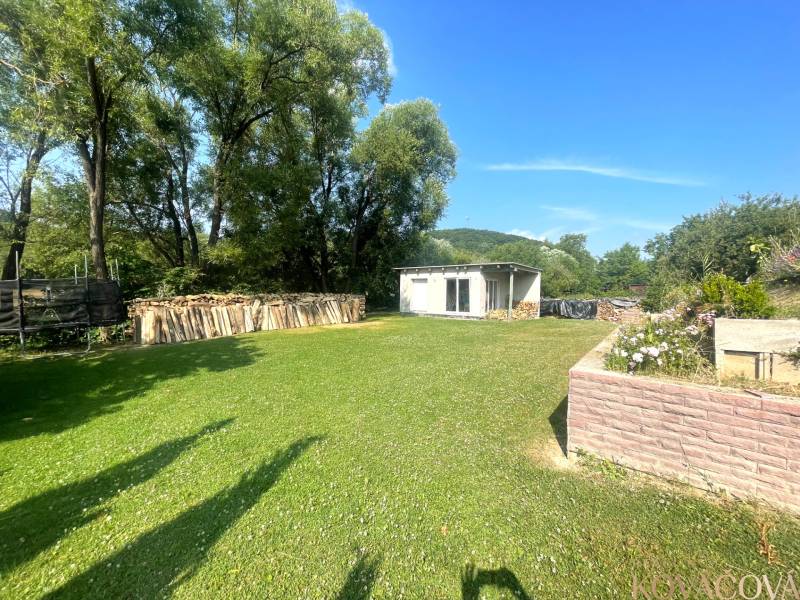 Garten bei einem Einfamilienhaus in Melčice-Lieskové mit Holz und einem Unterstand auf dem Rasen.
