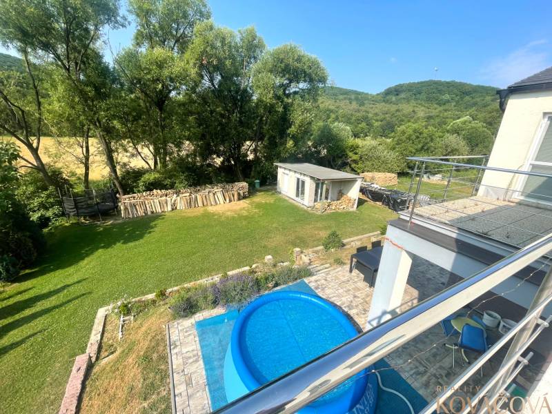 Der Garten des Einfamilienhauses in Melčice-Lieskové mit einem Pool, Bäumen und Brennholz.
