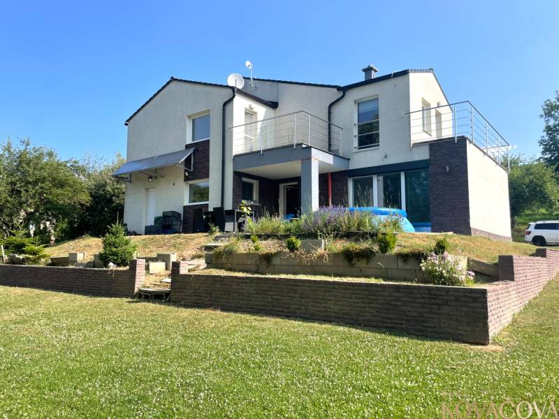 Ein Einfamilienhaus in Melčice-Lieskové mit Garten und Terrasse; Rasenfläche mit Blumen.