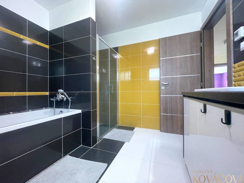 Ein Badezimmer in einem Einfamilienhaus mit Badewanne, Dusche und bunten Fliesen.