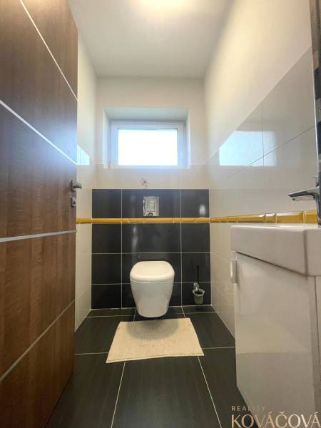 Badezimmer in einem Einfamilienhaus mit Toilette, hellen Wänden und schwarzen Fliesen.