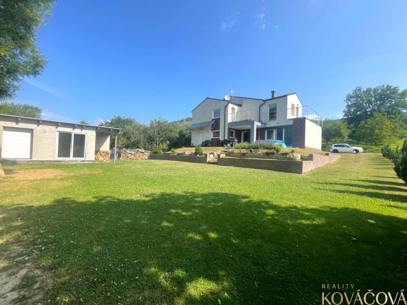 Ein Einfamilienhaus in Melčice-Lieskové, großer Garten, Garage, blauer Himmel, Sommertag.